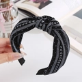 Close-up of knotted fabric headband with black and white floral patterns held by hand - Black Floral Knotted / Black