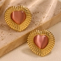 Detailed shot of gold heart earrings featuring pink cat eye stone and hammered metal finish - Gold Pink