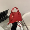 Red shell crossbody bag with snake skin pattern and gold zippers shown held by hand - Red