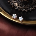 Gros plan de boucles d'oreilles perles en forme d'étoile sur velours rouge foncé - Petite Forme d'Étoile