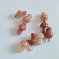 Pink and reddish natural stone mushroom pendants with silver metal clasps on white background - Purple Aventurine