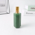 Grüner hexagonaler Kristall Parfümflakon mit goldener Sprühpumpe auf weißem Tisch - Aventurin-Jade