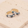 Detailed macro of gold-plated hoop earrings with blue enamel and floral patterns - Sapphire Blue