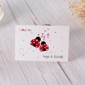 Textured white greeting card with ladybugs and hearts on a wooden desk with flowers - Ladybug