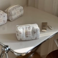 Nahaufnahme der cremefarbenen gesteppten Kosmetiktasche mit Bärenprints und Webeetikett - Gestreifter Elefant