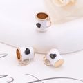 Detail view of gold alloy cup pendants with white enamel and black heart patterns - White