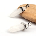 Macro shot of two hexagonal white crystal pendants with metal clasps on a wooden tray - White Crystal