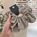 Oversized beige kanten scrunchie met zwarte stippen in de hand gepresenteerd - Grijsgroen