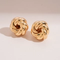 Detailed view of elegant gold-tone twisted knot stud earrings with polished metallic finish - Gold