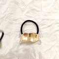 Black elastic hair tie with a gold wave-pattern metal cuff on white textured background - Gold Irregular Wave 5cm