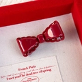 Detalle de pinza para el pelo con lazo rojo y bordes decorativos en caja de regalo - Estilo de Lazo Hueco / Rojo
