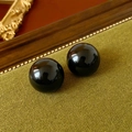 Macro shot of glossy black round beads on green fabric with vintage wooden accents - Black Round Lustrous Ball Studs