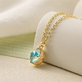 Macro di una collana d'oro con pendente in gemma blu ovale e piccoli diamanti brillanti - Pietra Preziosa Blu Ovale / Blu
