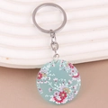 Detail of bohemian acrylic floral keychain with blue base and vibrant flower patterns - Light Blue