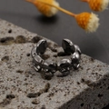 Macro shot of punk style skull ring with black metallic finish on dark stone background - Alloy / Triple Skull Ring / Gunmetal