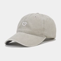 Detailed close-up of small white heart embroidery on a vintage washed khaki baseball cap - Beige