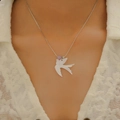 Gros plan d'un collier avec pendentif hirondelle argenté sur un haut en dentelle - Collier Oiseau (avec Perle Violette X373) / Argent