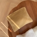 Dettaglio ravvicinato della borsa in lana di agnello color kaki su un tavolo di legno - Cammello Chiaro
