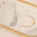 Close-up of pearl bead necklace with a small yellow fish pendant and gold clasp - Yellow
