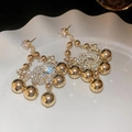 Détail macro de boucles d'oreilles fleurs dorées avec zircons sur une assiette blanche - Pendant Vintage Sphère Dorée (Tige en Argent)