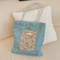 Detailed view of light blue denim tote with green sequins and floral patch on sofa - Floral Pattern + Sequin Denim