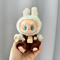Labubu doll wearing green rabbit plush coat and brown overalls with Happy Day text - Chocolate Happy Bear / First And Second Generation Keychains Are Compatible With La Cloth Dolls. Dolls Not Included.
