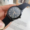 Detail of a black sports watch with golden hands and a silicone strap against a book - Black