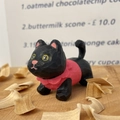 Close-up of hand-carved wooden cat figurine with pink details on light wood tabletop - Black Cat Style (Xiao Hei)
