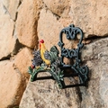 Vintage green cast iron garden hose holder with colorful rooster design on stone wall - 01167 Rooster Hose Holder