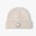 Chic cream white knitted beanie featuring a smiley face patch and double-cuff design - Beige
