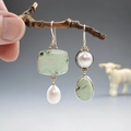 Orecchini asimmetrici in smalto verde chiaro con perle appesi a un ramo di legno naturale - Stile K