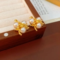 Détail de boucles d'oreilles vintage en or avec trois perles blanches en grappe dorée - Or / Doré