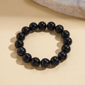 Macro detail of polished black acrylic beaded bracelet on a textured stone surface - Black