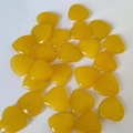 Polished yellow stone heart ornaments for crafts and jewelry making on white background - Orange