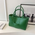 Detalle de bolso tote trenzado verde que muestra la textura de cuero sintético y acabado - Verde
