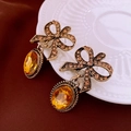 Dettaglio orecchini a fiocco vintage con strass e gemma ambrata su piatto in ceramica - Stile Pendente a Fiocco / Oro (Perno per orecchini in argento sterling 925)