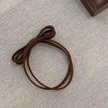 Braided brown elastic hair tie with a simple knot on a beige textured fabric - Light Coffee