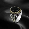 Macro shot of punk style ring with black gemstone and golden crown setting detail - US 7