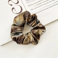 Elegant metallic shimmering scrunchie in gold and brown tones on an open magazine - Gradient Metallic Satin