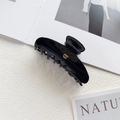 Detail shot of a glossy black hair claw clip featuring a metallic gold letter B logo - Gold B Logo / Black
