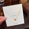 Collana in titanio dorato con ciondoli a cuore e chiave su un biglietto di auguri - Combinazione Cuore e Chiave (X246) / Oro