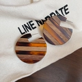 Detailansicht geometrischer Holzohrringe mit Bernsteinharz auf Leinenstoff - Silberner Ohrstecker - Kaffee