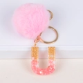 Detailed view of pink faux fur pompom keychain with resin letter U and gold foil - Letter U