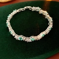 Detailed macro of silver tennis bracelet with green emerald stones and zircon accents - Blue