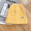 Bright yellow knitted beanie hat with California 1982 patch on a wooden background - M / Milk Yellow