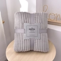 Grey flannel blanket with ribbed texture and decorative ribbon on a wooden table - Light Gray