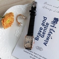 Close-up of retro rectangular rose gold watch with black leather strap on a ceramic plate - Black