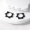 Close-up of black punk rivet huggie earrings with five cone spikes on stone - Black