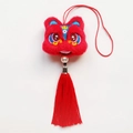 Dettaglio del ciondolo leone in peluche rosso con ricamo fine e lunga nappa di seta - Leone Felice (Rosso)