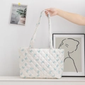 Close-up of white quilted tote bag with blue bow patterns and diamond stitch texture - White Base Blue Bow